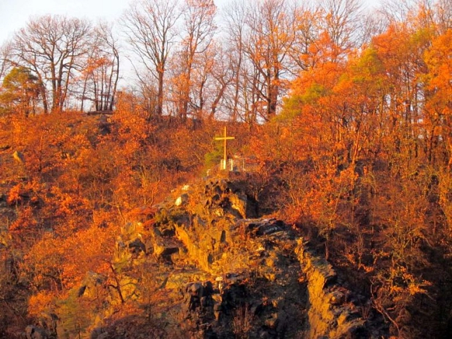 Aussichtsblattform Kreuzfelsen im Wald auf einem Fels. Die Herbstliche Landschaft zeigt einen Felsen umgeben von Wald, die Bäume tragen rote Blätter.
